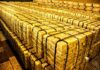 Stacks of gold bars strapped together in a vault