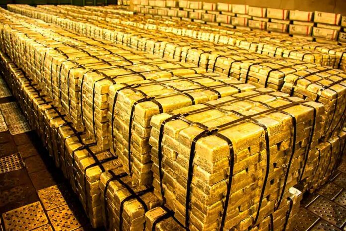 shutterstock_1930187009 Stacks of gold bars strapped together in a vault