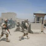 Iran-Backed Drone Kills U.S. Troops Soldiers in desert uniforms run past a checkpoint amid dust