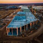 Farmland Bulldozed For Server Cities aerial view of large industrial building under construction at sunset