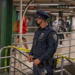 Police officer stands in a subway station near caution tape