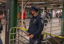 A Cop’s Gun Went Off Underground in Brooklyn Police officer stands in a subway station near caution tape