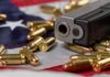 DOJ Blinks On Gun Law Handgun with bullets on an American flag