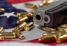 DOJ Blinks On Gun Law Handgun with bullets on an American flag