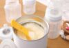 Infant formula powder with yellow scoop in open can