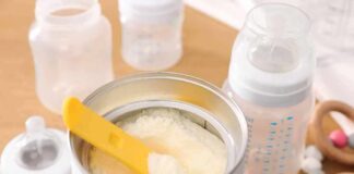 Infant formula powder with yellow scoop in open can
