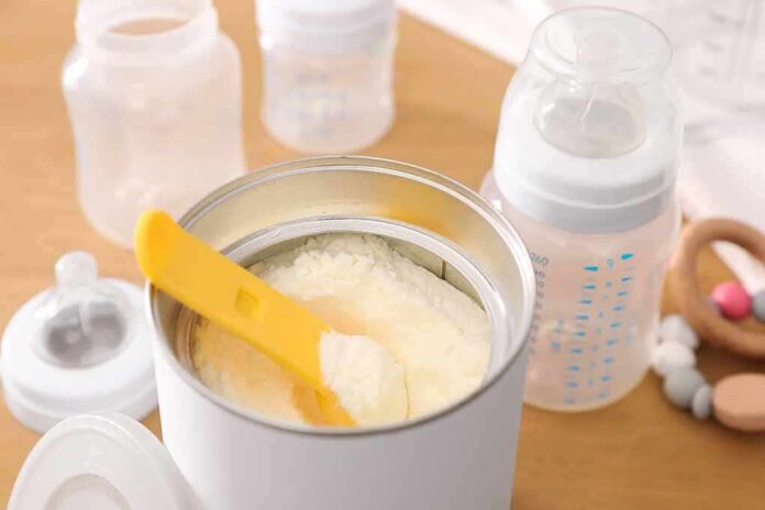Infant formula powder with yellow scoop in open can