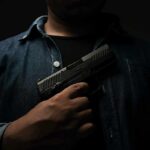 person holding a handgun against chest
