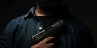 person holding a handgun against chest
