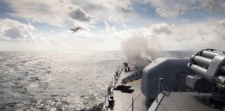 naval warship firing deck gun at sea