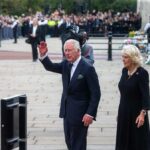 Grim Claim Haunts King Charles Charles, Prince of Wales waves while walking outdoors with a woman