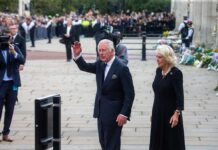 Grim Claim Haunts King Charles Charles, Prince of Wales waves while walking outdoors with a woman