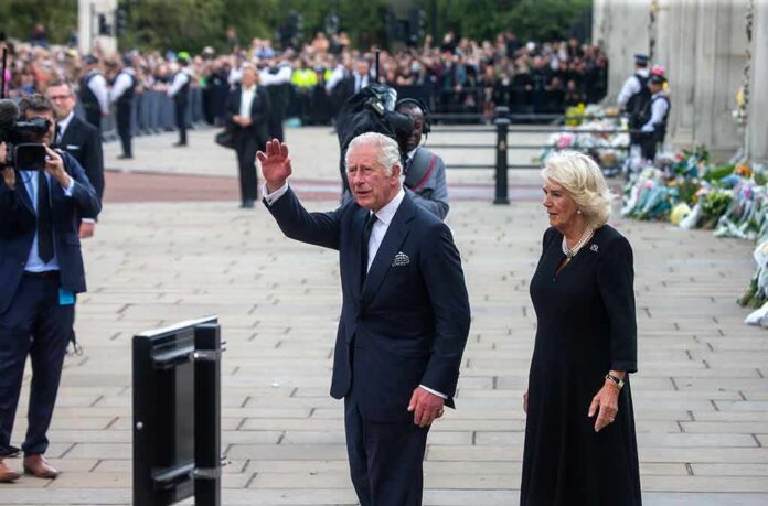 shutterstock_2200956097 Charles, Prince of Wales waves while walking outdoors with a woman
