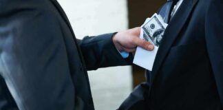 Businessmen handshake as cash is slipped into a suit pocket