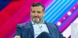 Ted Cruz seated on stage in a blue suit