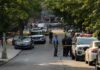 Downtown Shootout Turns Deadly Mystery Police officers secure a residential street with patrol cars and yellow tape