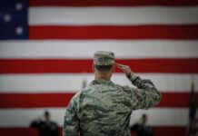 Soldier saluting before a large American flag