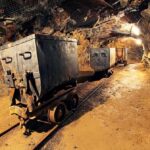 Mine carts on narrow-gauge tracks inside a rock tunnel