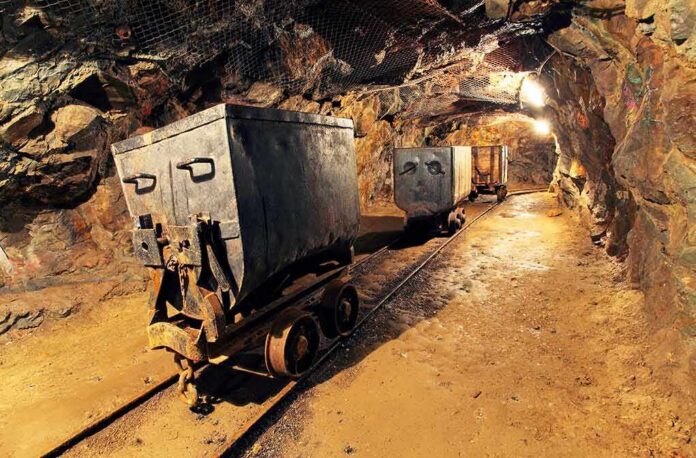 Mine carts on narrow-gauge tracks inside a rock tunnel
