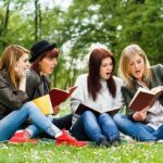 Tech Giant Forced To Make MASSIVE Payout Group of young women reading books on grass in a park