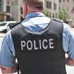 Impostor Cop Calls 911 – On Himself Police officer in uniform from behind on a city street