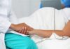 Grandmother Died Without Giving Final Consent Healthcare worker holding a patient's hand in a hospital bed