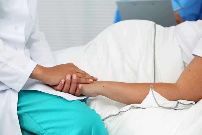 Healthcare worker holding a patient's hand in a hospital bed