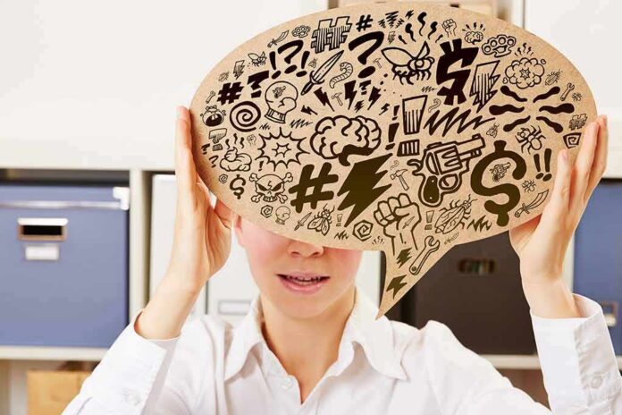 shutterstock_303568640 Person holding large speech bubble with chaotic doodles in office