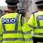 Two police officers in high-visibility jackets walking on a city street