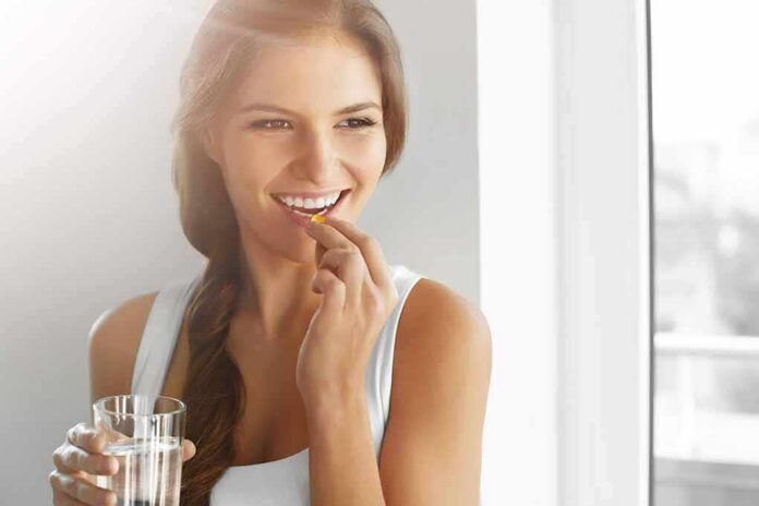 Woman holding a glass of water and taking a pill
