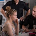 Feds Say Pizza Masked Meth Empire Young woman speaking with two officers at a desk