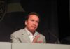 Arnold Schwarzenegger speaking at a podium with a microphone