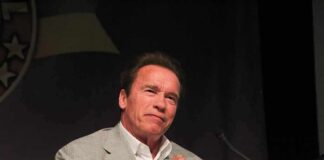 Arnold Schwarzenegger speaking at a podium with a microphone