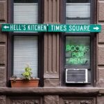 Apartment facade with windows, neon sign, and street direction sign