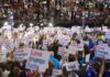 Christian Jones and Jonathan Cyprien in a crowded arena rally holding signs