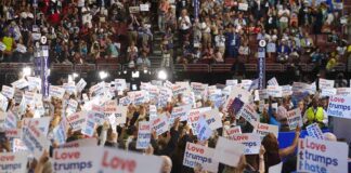 Christian Jones and Jonathan Cyprien in a crowded arena rally holding signs