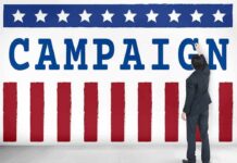 Man in suit writing on large campaign banner with stars and stripes