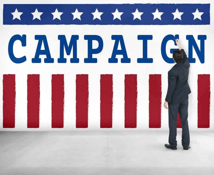 shutterstock_486646441-3 Man in suit writing on large campaign banner with stars and stripes