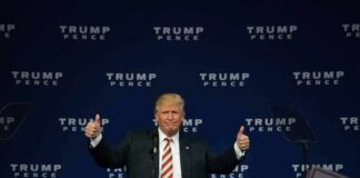man at podium giving two thumbs up
