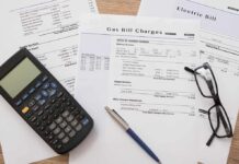 Utility bills with calculator, pen, and eyeglasses on a desk