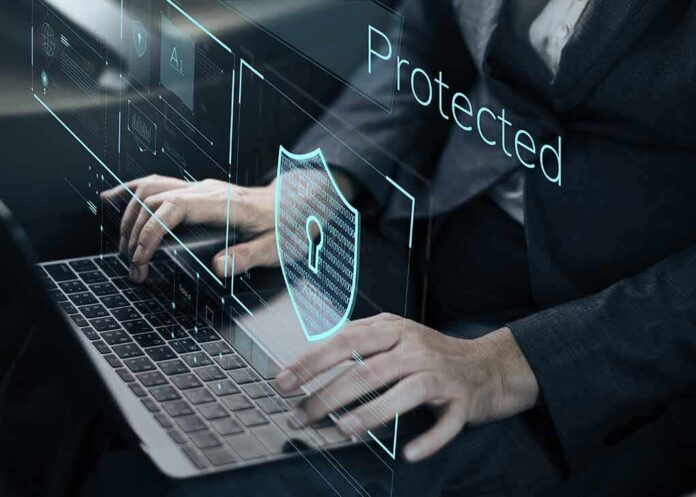 shutterstock_600760271 Person typing on laptop with digital security shield overlay
