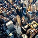 Rooftop Towers Suspected — UES Outbreak Grows Aerial view of dense downtown skyscrapers at sunset