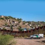 border fence with patrol truck in arid landscape