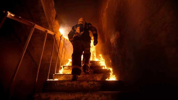 shutterstock_678730525 Firefighter climbing burning stairwell
