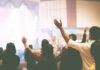 Pastor Gets Life for Raping Child as Wife Helped Enable Abuse Audience raising hands at indoor event