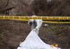 forensic investigator at outdoor crime scene behind caution tape