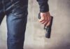 person holding a handgun by their side