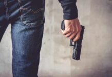 person holding a handgun by their side