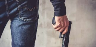 person holding a handgun by their side