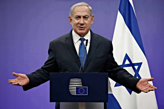 shutterstock_1046491414 man in suit speaking at a podium with Israeli flag
